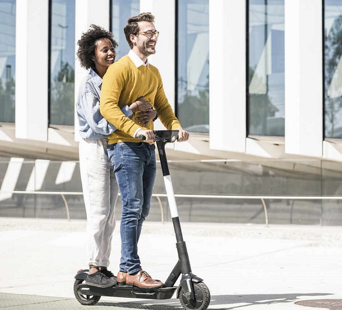 happy-young-couple-riding-e-scooter-in-the-city-UUF19642.jpg